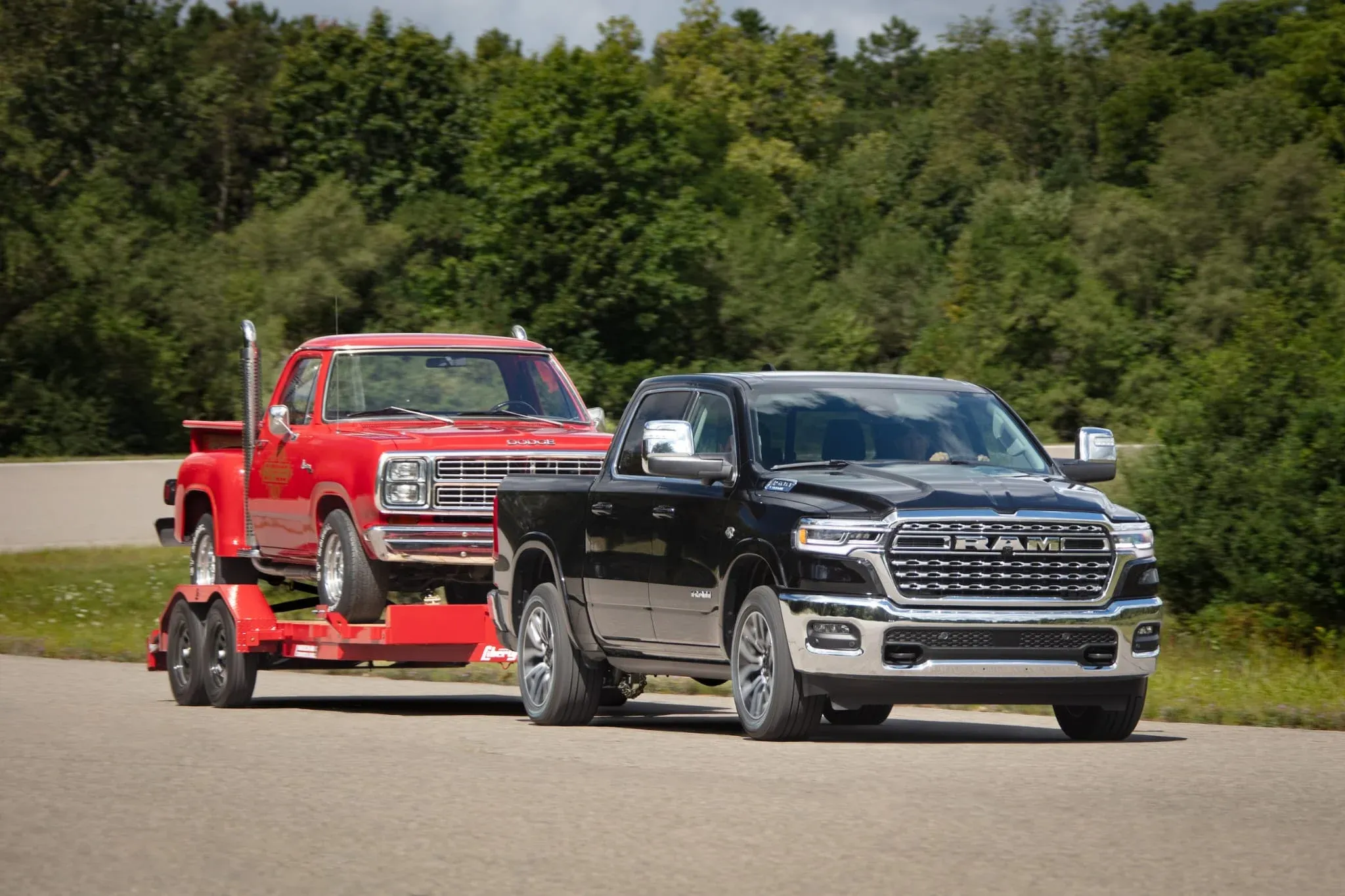 Truck towing a classic car on a flatbed trailer down the highway.